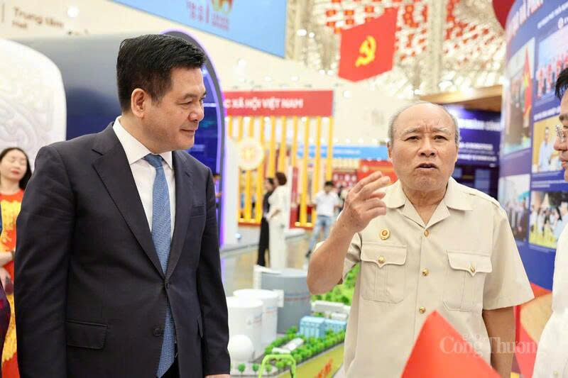 Minister of Industry and Trade Nguyen Hong Dien listens to the sharing of visitors to the National Achievements Exhibition