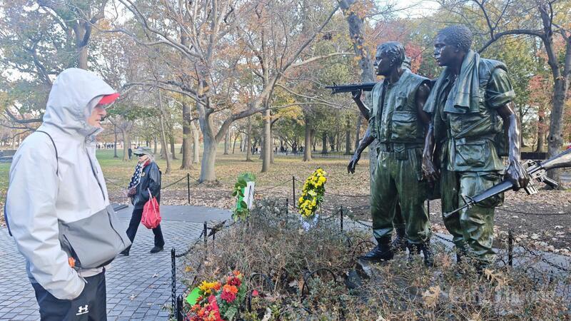 A young man stands before the Three Soldiers statue, near the Vietnam Veterans Memorial Wall.
