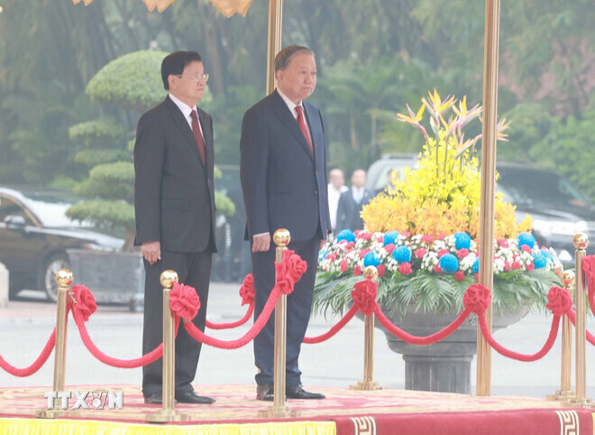 Party General Secretary To Lam and Lao Party General Secretary and President Thongloun Sisoulith stand on the ceremonial podium during the flag-raising ceremony. Photo: VNA