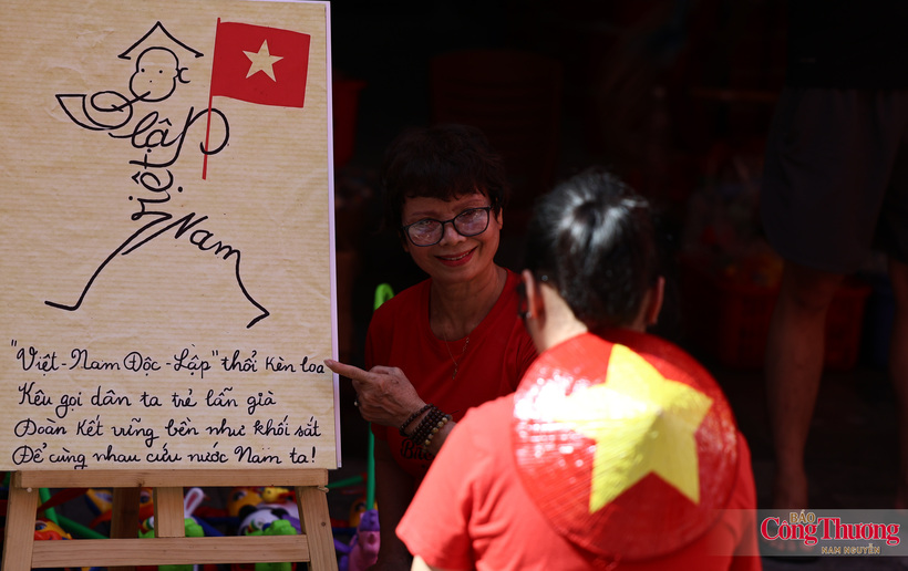 Residents pose for photographs beside the "Independent Vietnam" propaganda artwork.