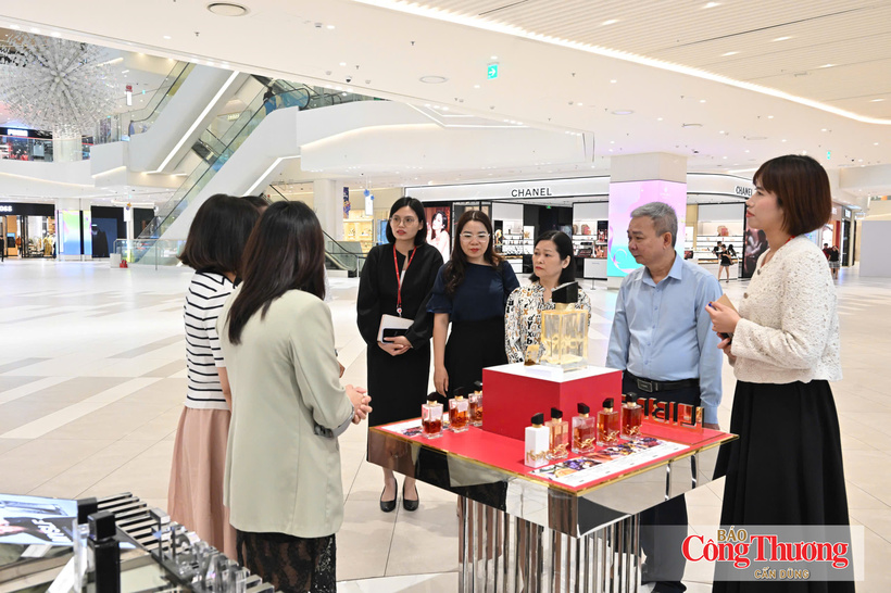 Deputy Editor-in-Chief of the Newspaper of Industry and Trade Nguyen Tien Cuong (in blue) and the delegation from the Newspaper of Industry and Trade visit a store at Lotte Properties Hanoi.