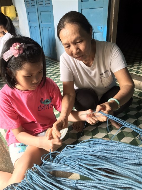 NEXT GENERATION: A girl learns how to make a fishing net at a home-stay service at Tân Diêm Village in the Sa Huỳnh salt fields. — Photo courtesy of SAHU NEXT GENERATION: A girl learns how to make a fishing net at a home-stay service at Tân Diêm Village in the Sa Huỳnh salt fields. — Photo courtesy of SAHU