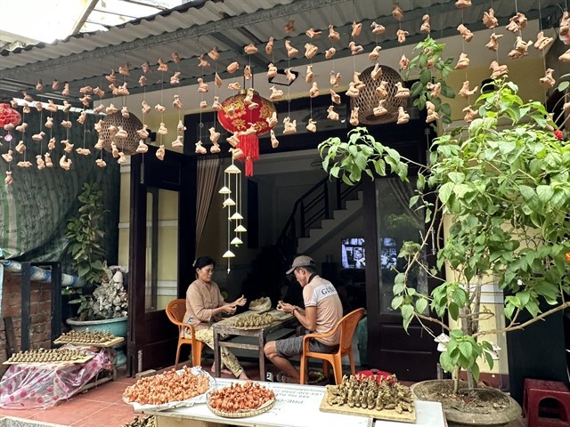 A family making con thổi. These ceramic whistles make a low and hollow sound when blown gently.  A family making con thổi. These ceramic whistles make a low and hollow sound when blown gently.