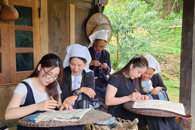 A group of Dao Tiền women instruct tourist Công Hải Anh (left) and her friend on beeswax pattern printing. — VNS Photo Lê Việt Dũng A group of Dao Tiền women instruct tourist Công Hải Anh (left) and her friend on beeswax pattern printing. — VNS Photo Lê Việt Dũng