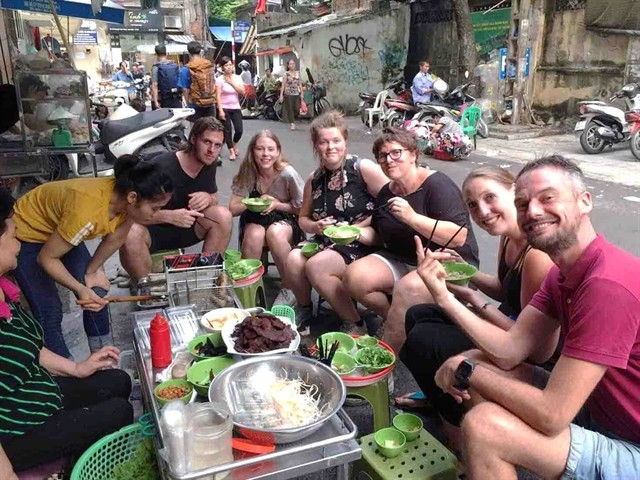 A group of foreign tourists enjoy street food in Hà Nội. Photo vietnamopentour.com.vn