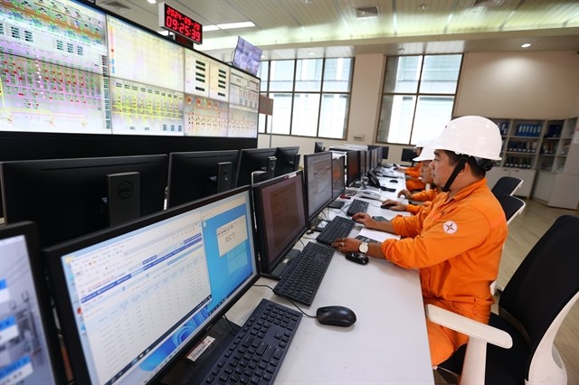 Workers operate production activities at the central control room of the hydropower plant.