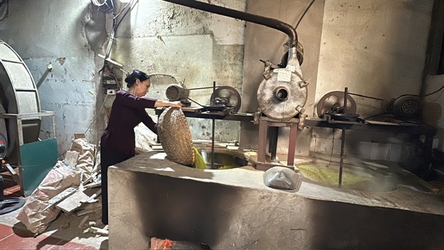 Tuyết pours green sticky rice grains into a big pan to roast. VNS Photo Lê Hương Tuyết pours green sticky rice grains into a big pan to roast. VNS Photo Lê Hương