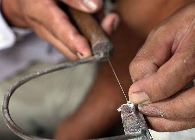 An artisan cutting mother-of-pearl and shell - the raw materials for mother-of-pearl inlay artwork.