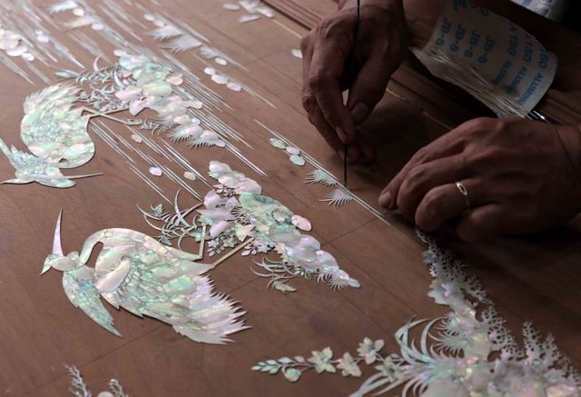 Placing mother-of-pearl pieces on wood before cutting.